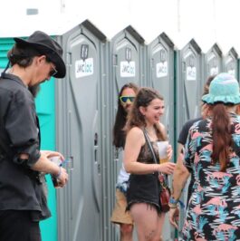 Groupe de festivaliers devant une rangée de toilettes mobiles WC Loc lors d’un événement en plein air.