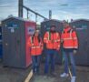 Trois ouvriers devant des cabines sanitaires femme et homme