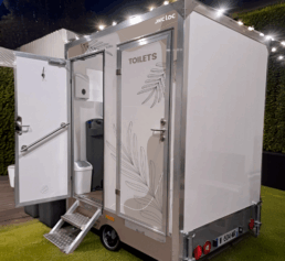 Caravane sanitaire FESTI de WC Loc, élégante et moderne, installée dans un espace extérieur.