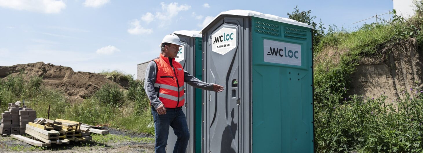 Opérateur sur un chantier utilisant une cabine WC Loc, illustrant la nécessité d’un lave-mains mobile pour garantir l’hygiène des travailleurs.