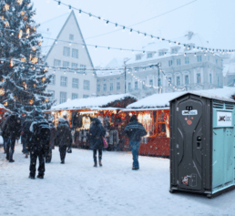 Cabine WC Loc installée en extérieur dans un environnement enneigé, à proximité d’un marché hivernal.