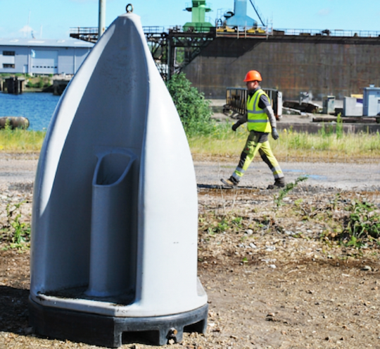 Urinoir autonome de chantier avec compagnon en gilet jaune en arrière-plan